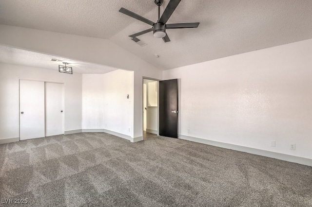 unfurnished bedroom with a textured ceiling, lofted ceiling, carpet floors, a closet, and ceiling fan