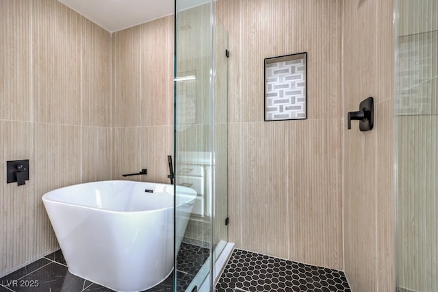 bathroom featuring tile walls and independent shower and bath