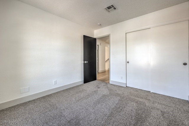 unfurnished bedroom featuring a textured ceiling, a closet, and carpet flooring