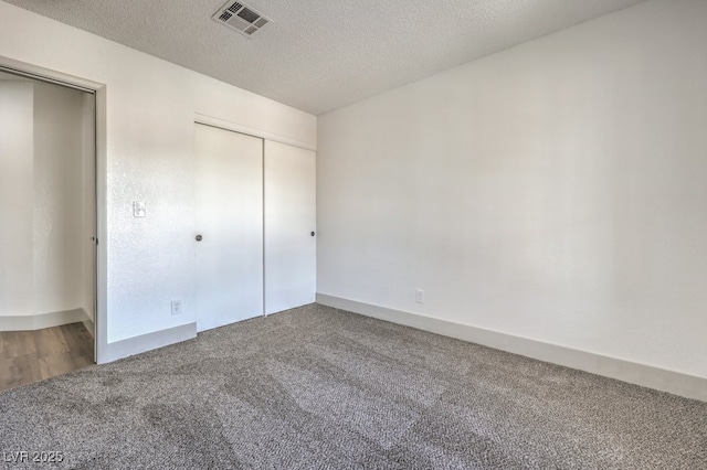 unfurnished bedroom featuring a textured ceiling, a closet, and carpet flooring