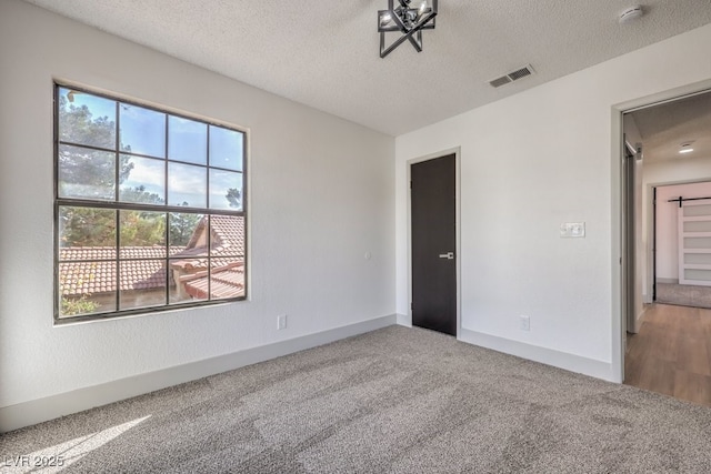 carpeted empty room with a textured ceiling