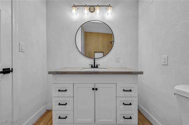 bathroom featuring toilet, vanity, and hardwood / wood-style floors