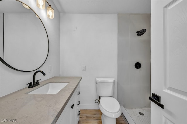 bathroom with toilet, a tile shower, and vanity