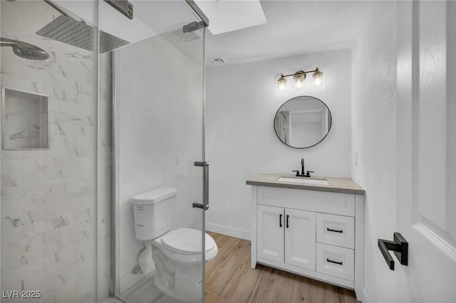 bathroom featuring toilet, vanity, wood-type flooring, and a shower with door