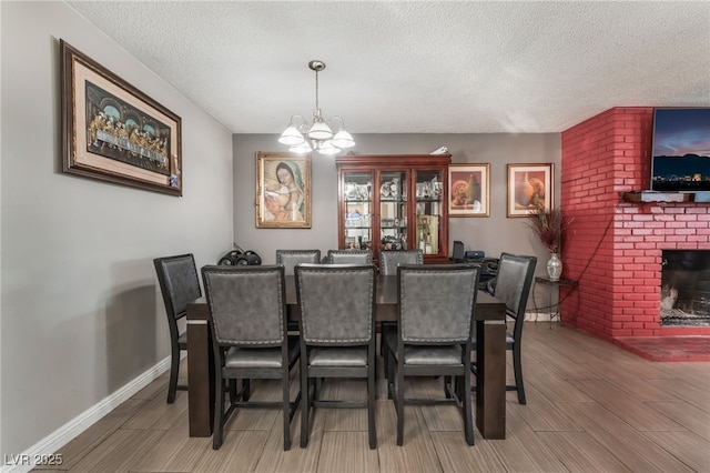 dining room with an inviting chandelier, a brick fireplace, and a textured ceiling