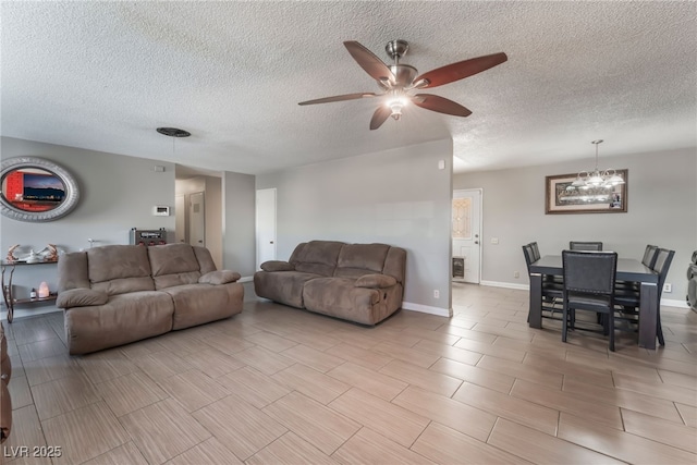 living room featuring ceiling fan with notable chandelier and a textured ceiling