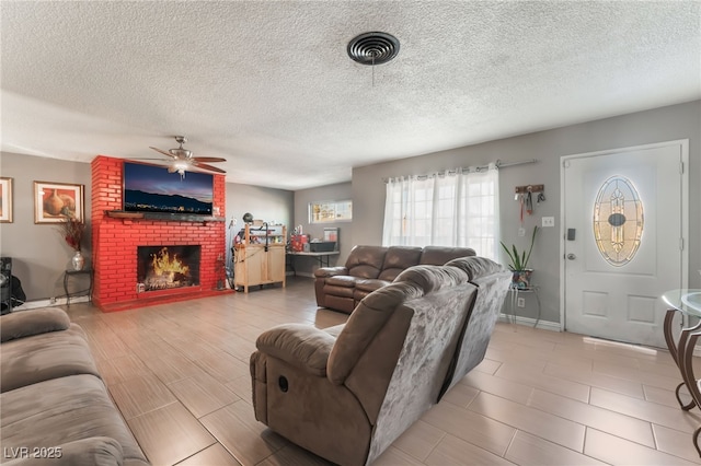 living room with a brick fireplace, a textured ceiling, and ceiling fan