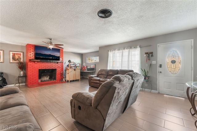 living room featuring a brick fireplace, a textured ceiling, and ceiling fan