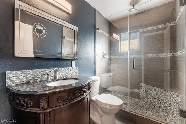 bathroom with tasteful backsplash, vanity, toilet, and a shower with shower door