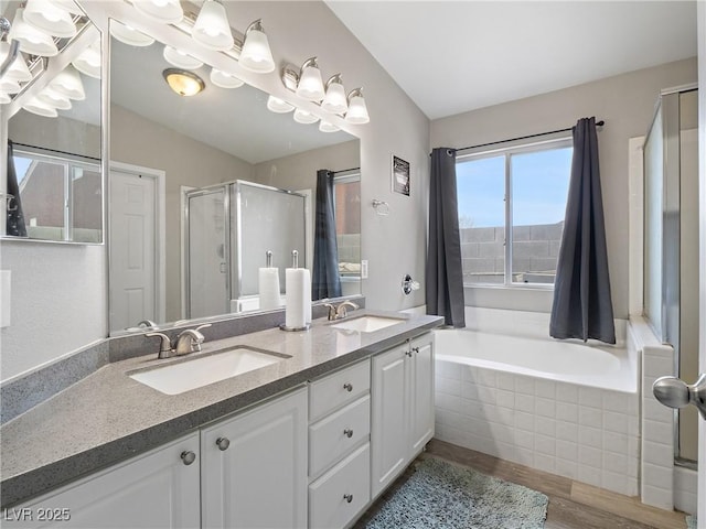 bathroom featuring a shower stall, a garden tub, double vanity, and a sink