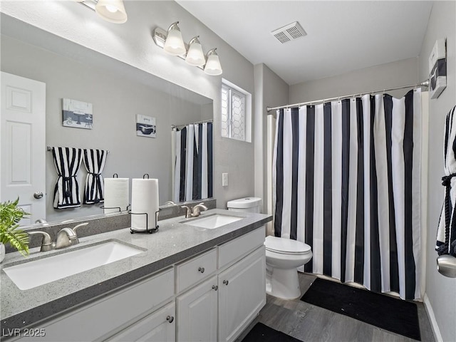 bathroom with double vanity, toilet, visible vents, and a sink