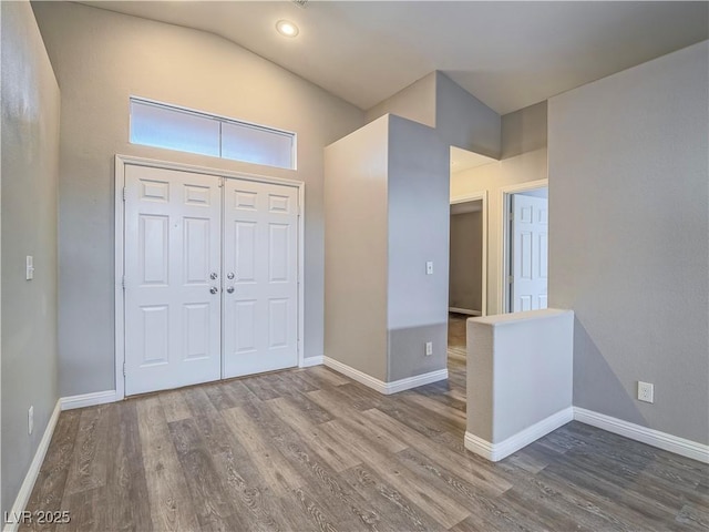 foyer with lofted ceiling, wood finished floors, and baseboards