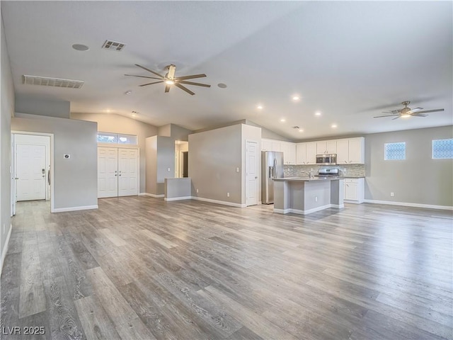 unfurnished living room with light wood-type flooring, visible vents, lofted ceiling, and a ceiling fan