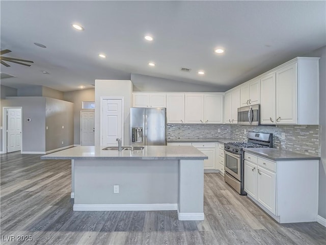 kitchen featuring visible vents, an island with sink, a sink, appliances with stainless steel finishes, and white cabinetry