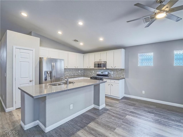 kitchen with visible vents, a kitchen island with sink, a sink, decorative backsplash, and appliances with stainless steel finishes