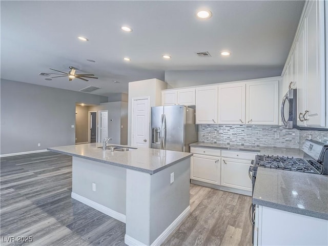 kitchen with visible vents, an island with sink, a sink, white cabinets, and appliances with stainless steel finishes