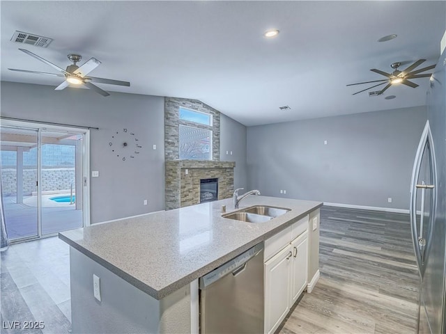 kitchen with visible vents, a sink, open floor plan, appliances with stainless steel finishes, and a stone fireplace