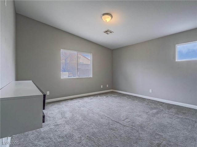 empty room with carpet, visible vents, and baseboards