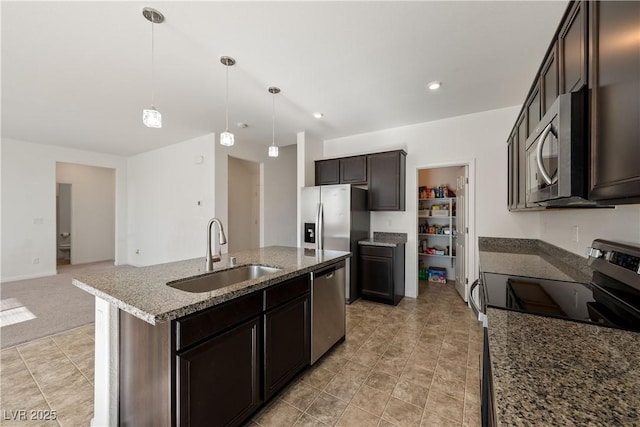 kitchen with appliances with stainless steel finishes, decorative light fixtures, sink, a kitchen island with sink, and dark brown cabinets