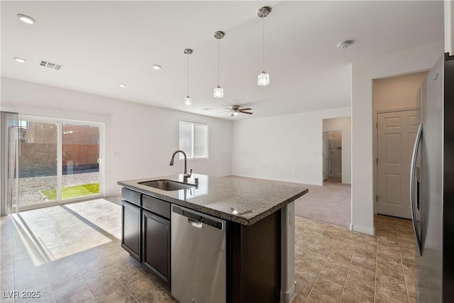 kitchen with light stone countertops, appliances with stainless steel finishes, sink, a kitchen island with sink, and ceiling fan