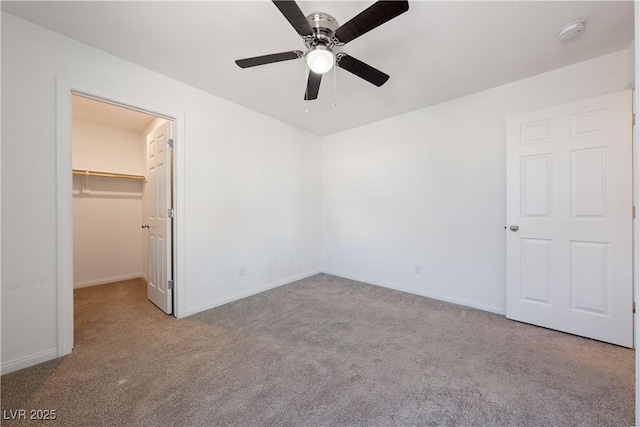 unfurnished bedroom with a spacious closet, light colored carpet, a closet, and ceiling fan