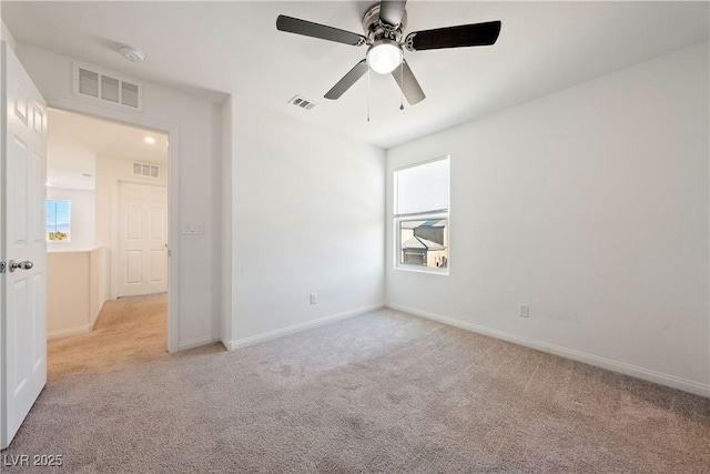 empty room featuring a healthy amount of sunlight, light colored carpet, and ceiling fan