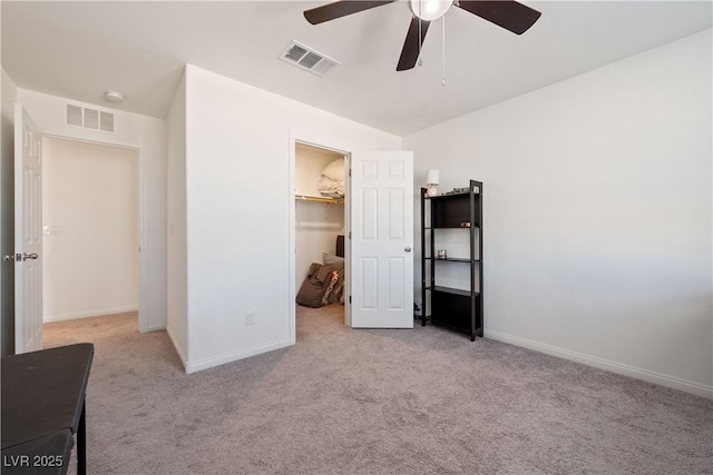 unfurnished bedroom with ceiling fan, light colored carpet, a spacious closet, and a closet