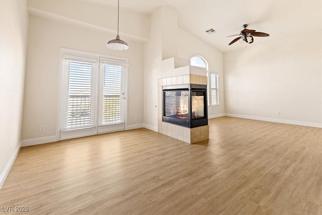 unfurnished living room featuring light wood-type flooring, ceiling fan, a multi sided fireplace, and vaulted ceiling