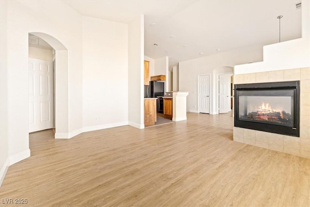 unfurnished living room featuring light hardwood / wood-style floors and a tiled fireplace