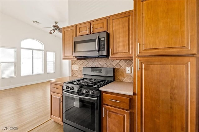 kitchen with ceiling fan, black gas range, tasteful backsplash, and light hardwood / wood-style flooring