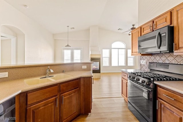 kitchen featuring pendant lighting, lofted ceiling, gas stove, tasteful backsplash, and sink