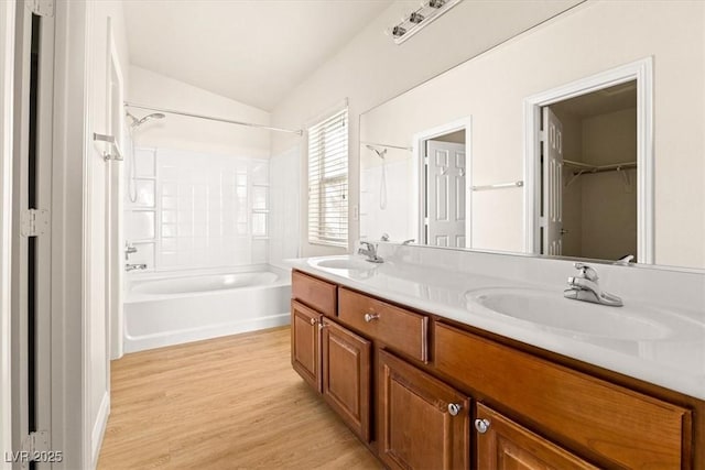 bathroom with lofted ceiling, shower / bath combination, hardwood / wood-style floors, and vanity