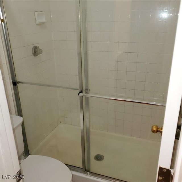 bathroom featuring toilet and an enclosed shower