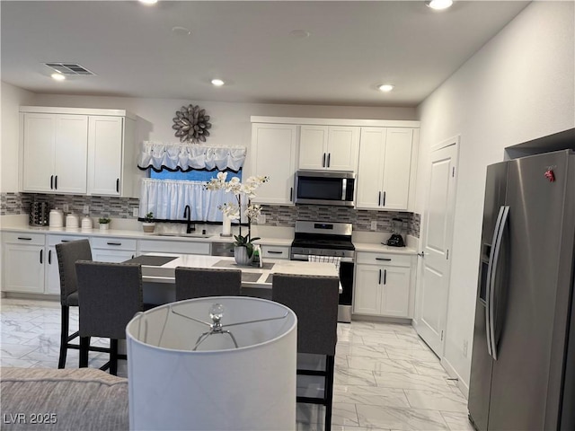 kitchen with appliances with stainless steel finishes, sink, white cabinetry, and a center island