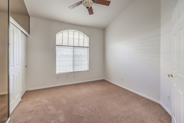 carpeted spare room featuring ceiling fan and lofted ceiling