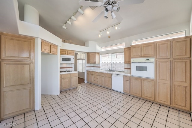 kitchen featuring tasteful backsplash, ceiling fan, sink, white appliances, and light tile patterned floors