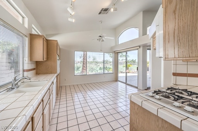 kitchen with ceiling fan, sink, decorative backsplash, and tile countertops