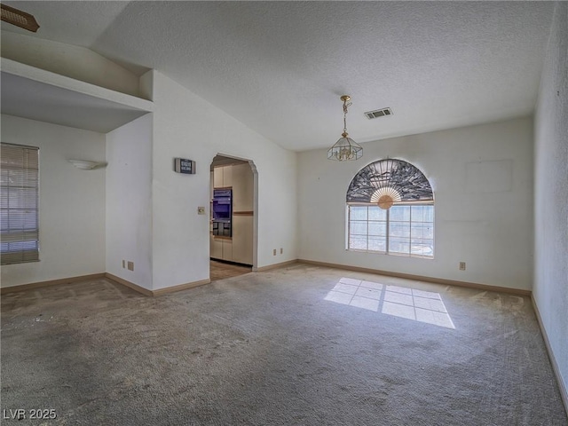 carpeted spare room featuring a textured ceiling, lofted ceiling, and a notable chandelier