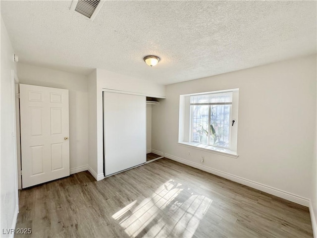 unfurnished bedroom featuring a textured ceiling, a closet, and light hardwood / wood-style floors