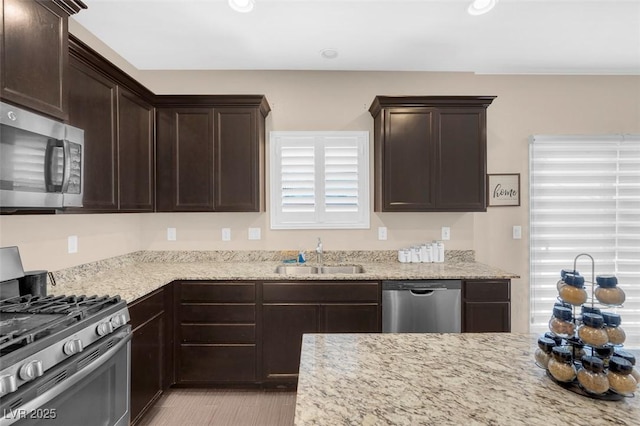 kitchen featuring light stone countertops, appliances with stainless steel finishes, sink, and dark brown cabinets