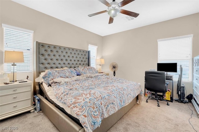 bedroom featuring ceiling fan, light colored carpet, and multiple windows