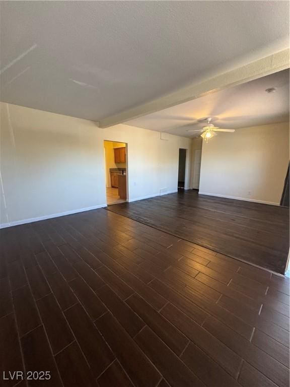 unfurnished room featuring ceiling fan, dark hardwood / wood-style floors, and beamed ceiling