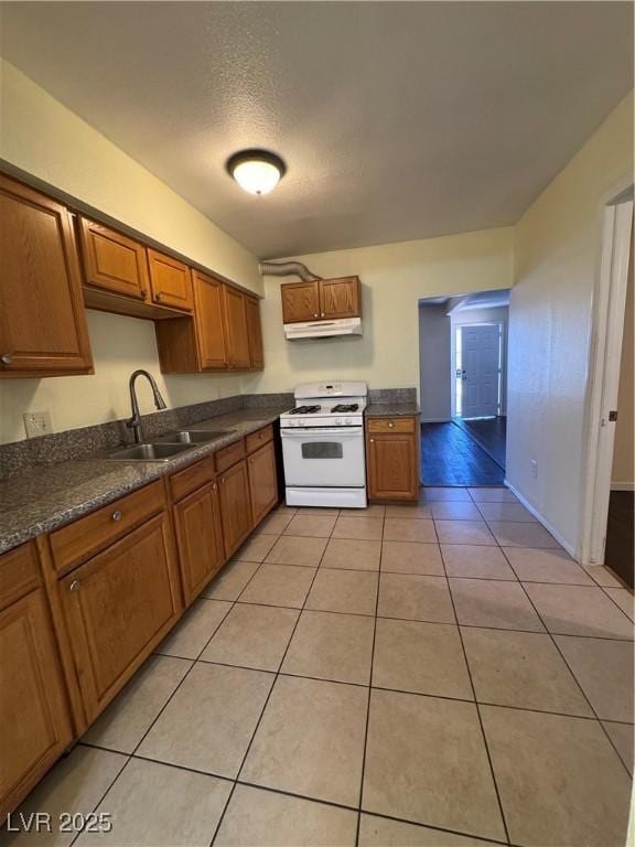 kitchen featuring light tile patterned floors, sink, and white gas stove