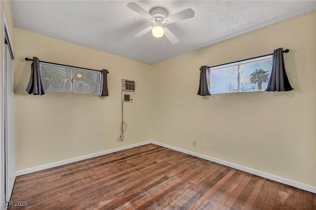 unfurnished room featuring a wall mounted air conditioner, ceiling fan, wood-type flooring, and a textured ceiling