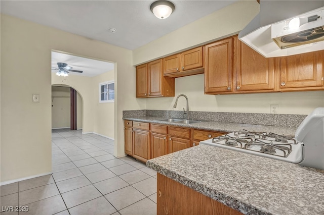 kitchen featuring light tile patterned floors, sink, stove, exhaust hood, and ceiling fan