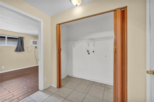 clothes washing area featuring a wall unit AC and light tile patterned flooring