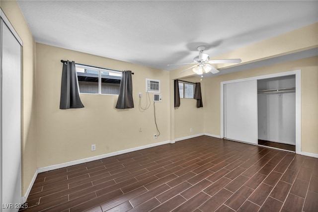 unfurnished bedroom featuring a wall mounted AC, a closet, dark hardwood / wood-style floors, and ceiling fan