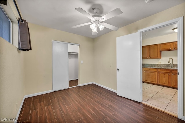 unfurnished bedroom featuring dark hardwood / wood-style flooring, ceiling fan, sink, and a closet