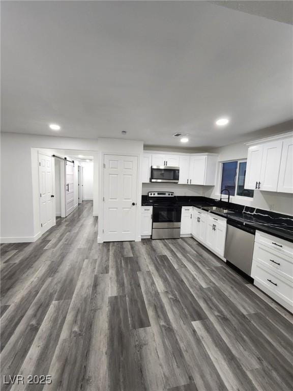 kitchen featuring dark wood-type flooring, stainless steel appliances, white cabinets, and sink