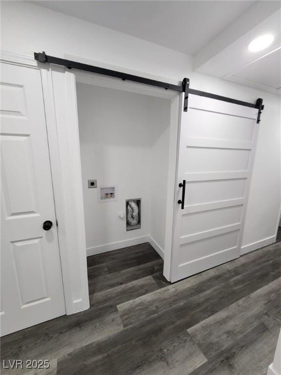 washroom featuring a barn door, washer hookup, dark hardwood / wood-style floors, and hookup for an electric dryer